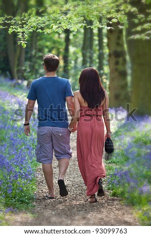 Loving young Couple Walking happily Hand in Hand in bluebell woods