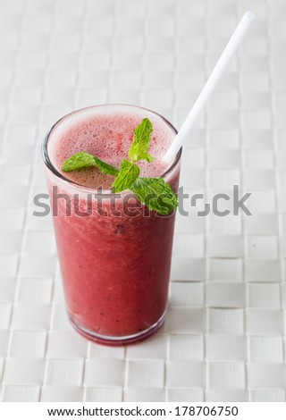Watermelon shake with a straw and a mint leaf.
