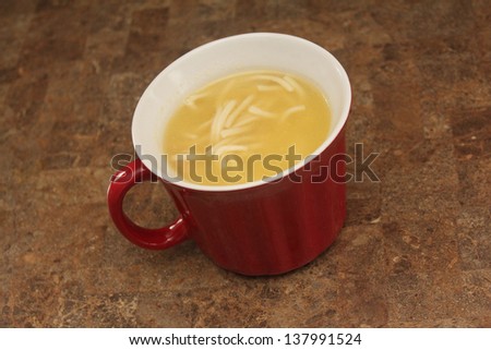 chicken noodle soup in red cup on counter top