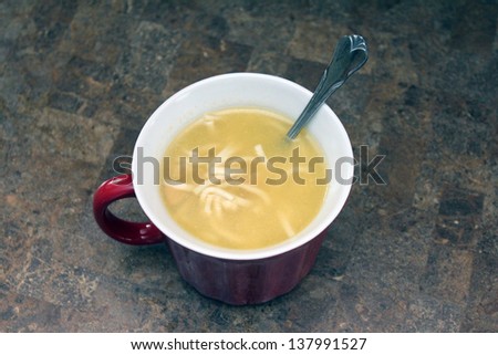 chicken noodle soup in red cup on counter top