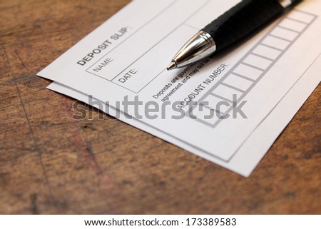 paper deposit slip and pen over wood background