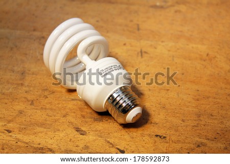 Compact fluorescent light bulb isolated over wood background