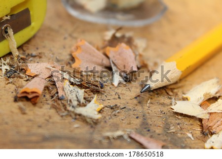Yellow pencil with shavings and pencil sharpener on rustic wood