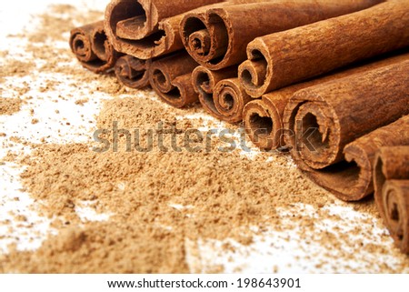 Cinnamon sticks with its dust around it over a white background
