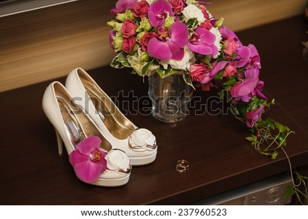wedding rings and bride\'s shoes on the desk