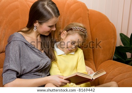 Mother and daughter reading book in the room