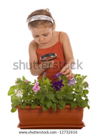 Young girl is looking through a magnifying glass and researching a flower