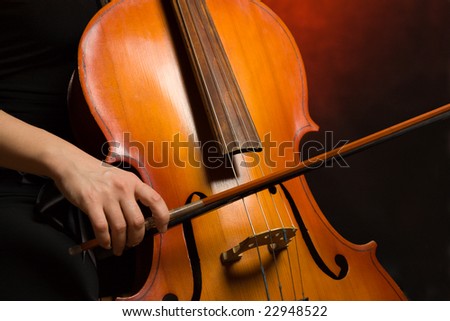 Close up musician hands with cello on a dark background