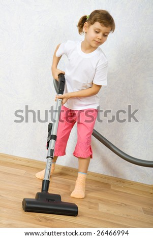 Little girl cleaning floor with vacuum cleaner