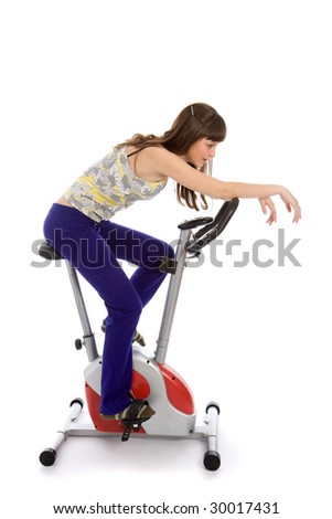 Teenager girl doing fitness on a stationary bike isolated on white