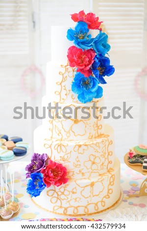 Big festive cake with flowers and other decorations on the table.
