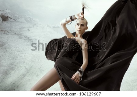 Beautiful young woman posing in long black dress with chain on hand, in fashion image. Makeup, hairstyle.