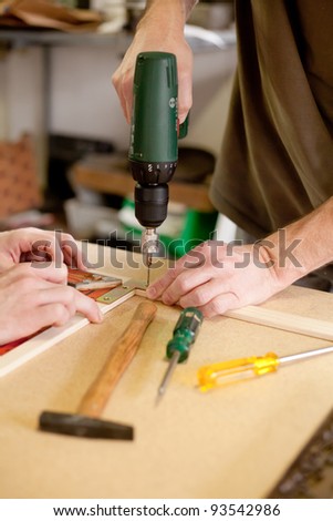 drilling a hole in the wood with an electric drill