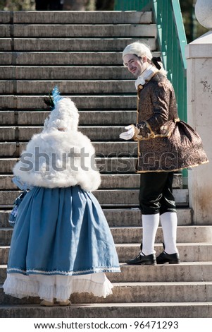 VENICE, ITALY- FEBRUARY 21: A masked man gives a helping hand to a masked woman during Venice carnival on February 21, 2012 in Venice