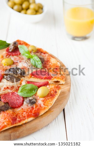 half a pizza with cheese and salami on board, closeup food