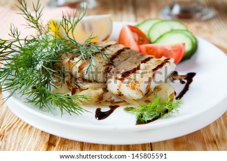 fish on a pillow with onion sauce and vegetables, close up food