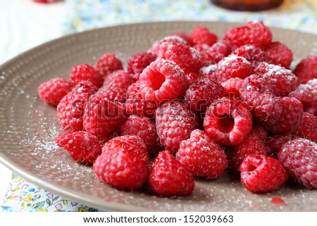 ripe raspberries on a plate with icing sugar, food close up