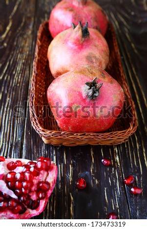 three pomegranate on a wicker tray, food closeup