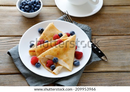 summer crepes with berries on white plate, food closeup