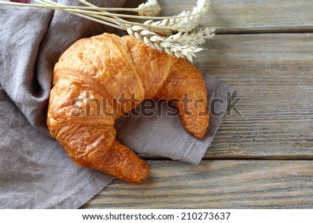 one ruddy French croissant on the boards, food closeup