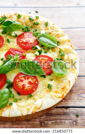 Pizza with cheese tomatoes and greens, side view