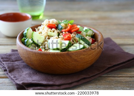 Pearl barley with cucumbers and pepper in a wooden bowl. Salad, healthy food