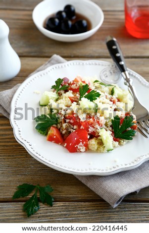 Salad with cooked couscous and vegetables on a white plate, nutritious food