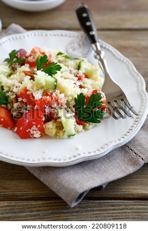 Salad with couscous and fresh vegetables on the plate, nutritious food