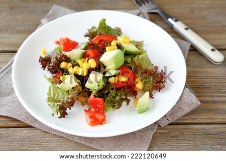 salad with avocado, tomatoes and corn on a white plate, nutritious food