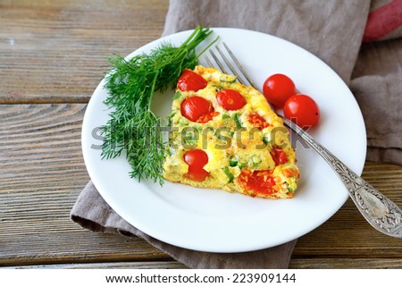 Frittata piece on white plate, wooden background