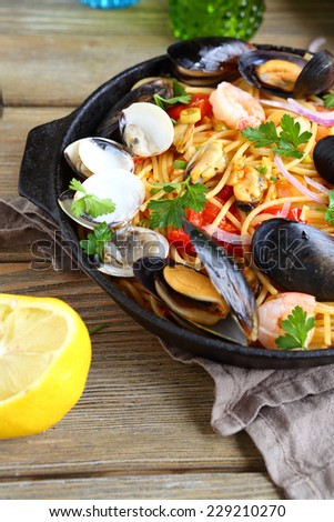 Pasta with mussels, squid and parsley in a frying pan, seafood
