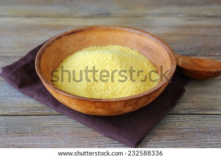 Uncooked couscous in a clay bowl on wooden boards, arabic food