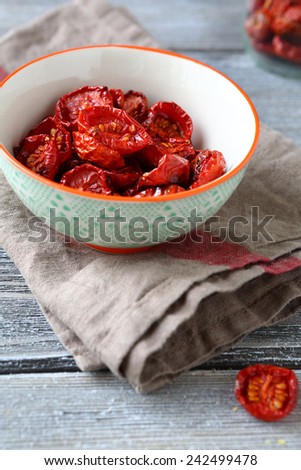 Sun dried cherry tomatoes in a bowl on napkin, wooden boards