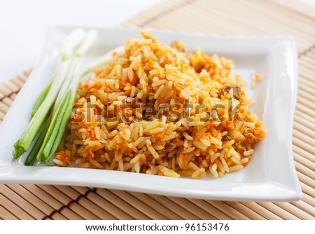 Rice with green onions and brown bread on a white square plate.  Isolated on white