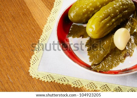 Plate with marinated cucumbers, garlic and leaf of currant