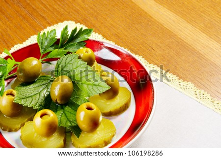 Plate with cucumbers, olive and leaf of punch and currant on wooden table