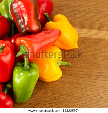 Vegetarian cuisine. Multi-coloured pepper on a wooden table