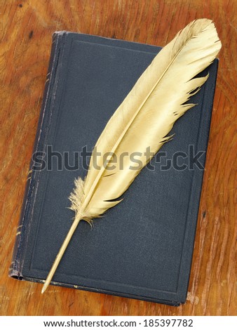 Gold quill pen and dark blue book on grunge wood board