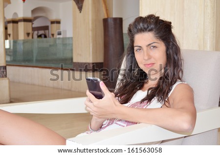 Young smiling pretty woman talking on her mobile phone in the hotel lobby