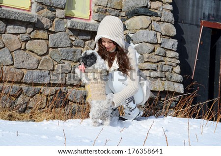 beautiful young woman enjoying the time spent with her dog in the winter mountain