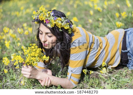 beautiful brunette woman with flower wreath laying in a meadow with yellow flowers