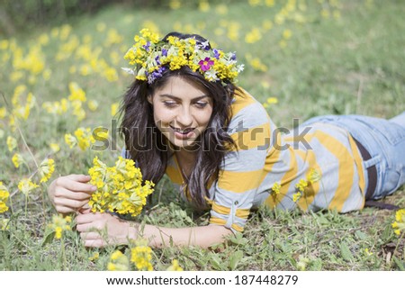 beautiful brunette woman with flower wreath laying in a meadow with yellow flowers