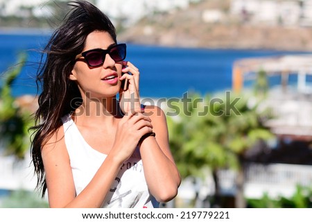 Portrait of beautiful young woman talking on the phone on a sea background