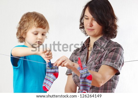 A little boy helps her mother to hang up your clothes