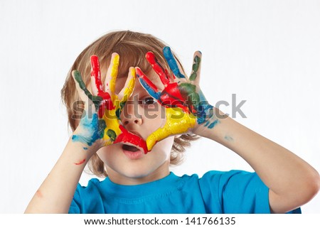 Little blond boy with painted hands on a white background