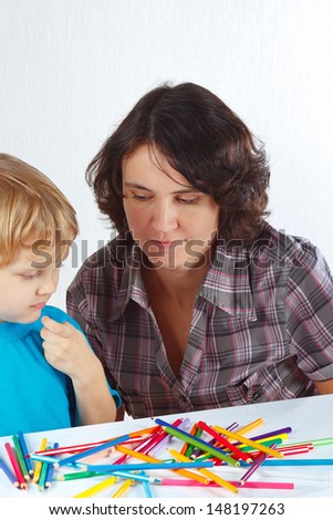 Little cute boy with his mother draws with color pencils on a white background