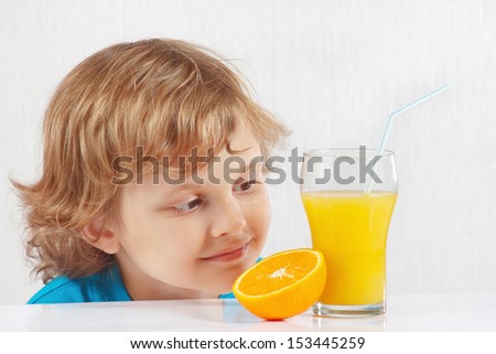 Young blonde boy with a glass of fresh juice and orange