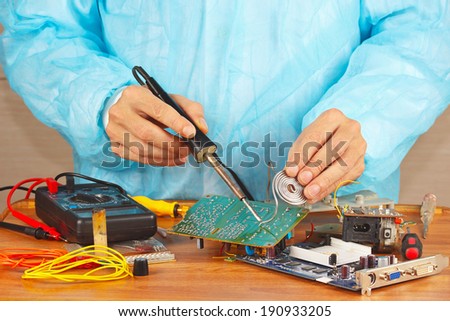 Serviceman solder electronic board in the service workshop