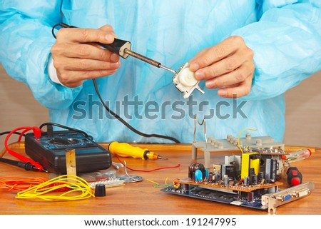 Serviceman solder electronic hardware in the service workshop