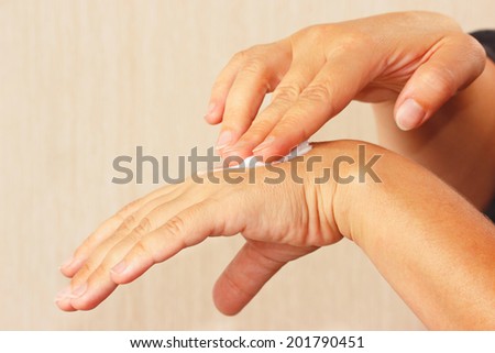 Female hands using a cosmetic skin cream